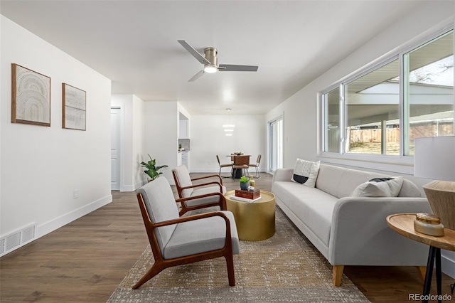 living room with visible vents, baseboards, wood finished floors, and a ceiling fan