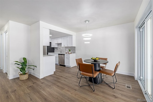 dining space featuring visible vents, baseboards, and wood finished floors