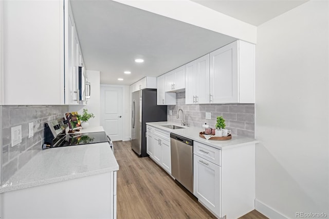 kitchen with a sink, light wood-type flooring, appliances with stainless steel finishes, and white cabinets