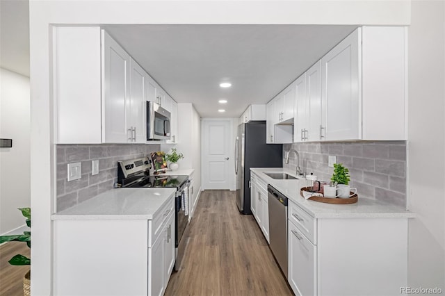 kitchen with a sink, stainless steel appliances, light countertops, light wood-style floors, and white cabinetry