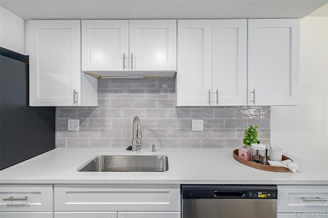 kitchen with stainless steel dishwasher, backsplash, white cabinetry, and a sink