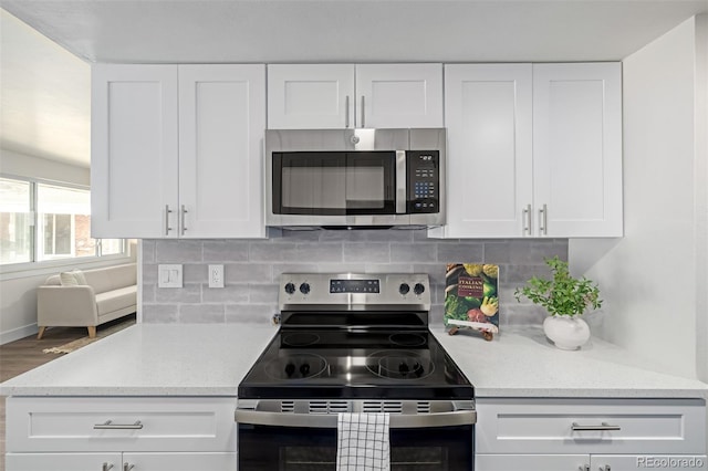 kitchen featuring decorative backsplash, white cabinets, light stone countertops, and stainless steel appliances