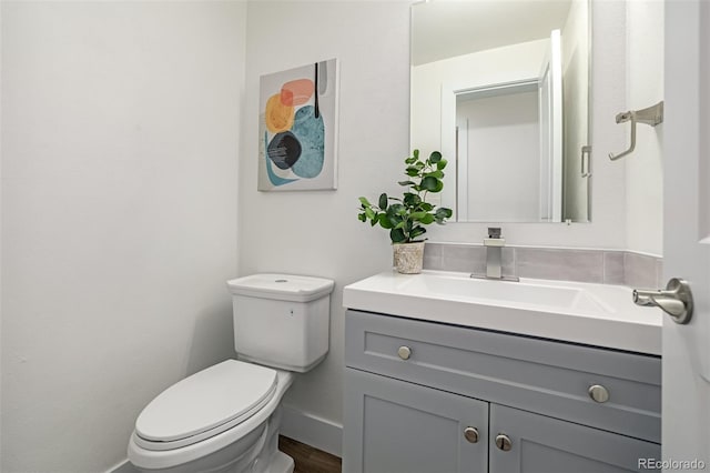 bathroom featuring toilet, vanity, and baseboards