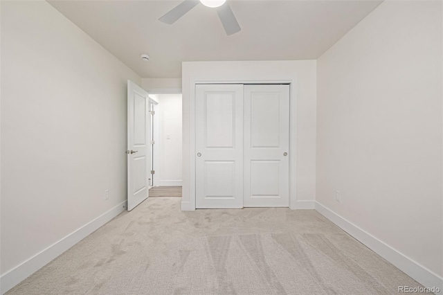 unfurnished bedroom featuring a closet, light colored carpet, baseboards, and ceiling fan