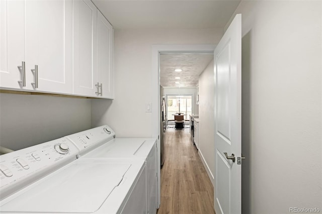 clothes washing area featuring cabinet space, light wood-style floors, and independent washer and dryer