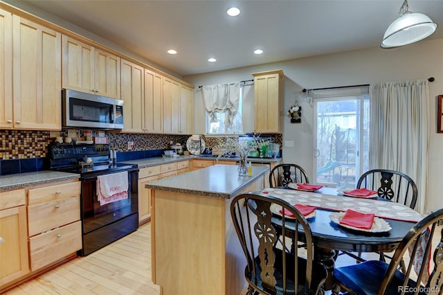 kitchen featuring black electric range oven, decorative light fixtures, light brown cabinets, and a kitchen island