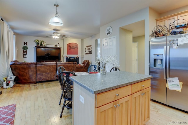 kitchen with hanging light fixtures, a kitchen island, light brown cabinetry, stainless steel fridge with ice dispenser, and light wood-type flooring