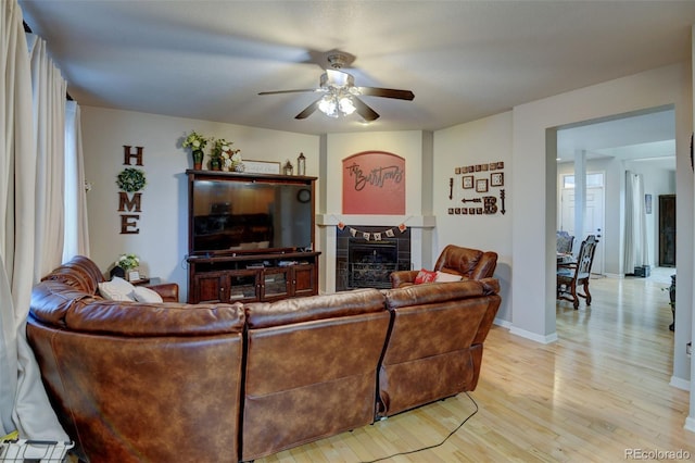 living room featuring light hardwood / wood-style floors, a tile fireplace, and ceiling fan