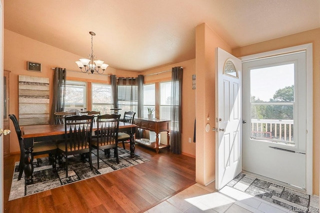 dining space featuring hardwood / wood-style floors, a notable chandelier, and lofted ceiling