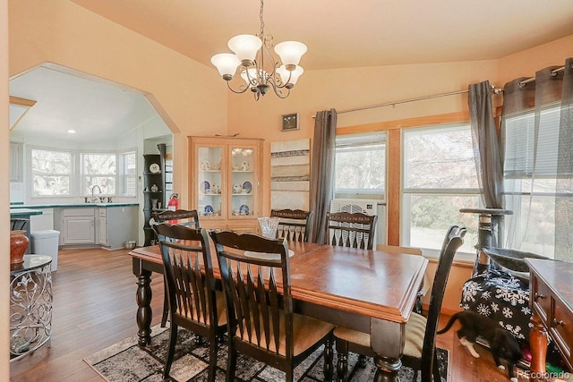 dining space with a chandelier, hardwood / wood-style flooring, lofted ceiling, and sink