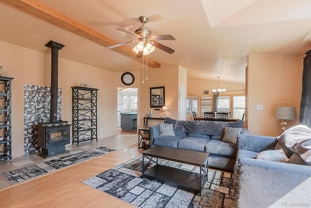 living room with hardwood / wood-style flooring, lofted ceiling with beams, a wood stove, and ceiling fan with notable chandelier