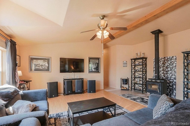 living room featuring vaulted ceiling with beams, light hardwood / wood-style flooring, a wood stove, and ceiling fan