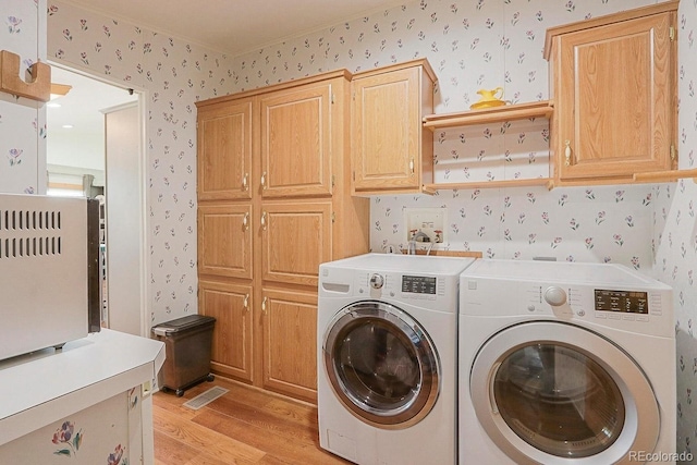 washroom with cabinets, independent washer and dryer, and light hardwood / wood-style flooring