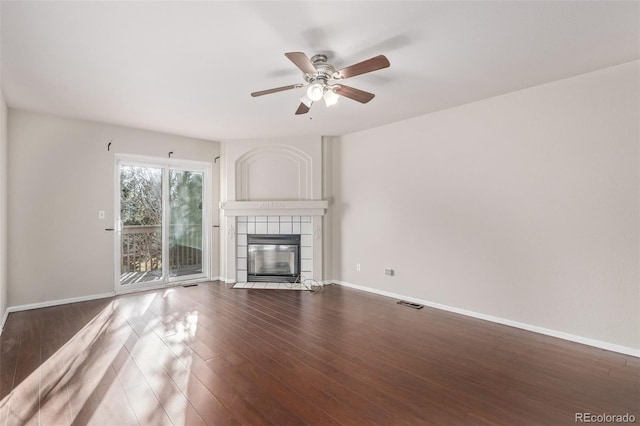 unfurnished living room featuring ceiling fan, dark wood-type flooring, and a tiled fireplace