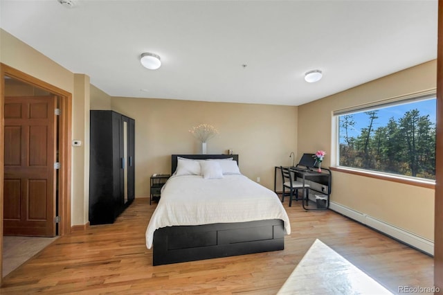 bedroom with light wood-type flooring and a baseboard heating unit