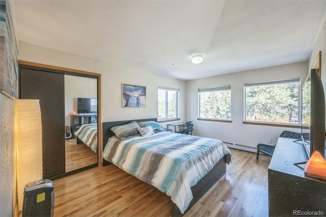 bedroom featuring a closet, a baseboard radiator, a textured ceiling, and light wood-type flooring