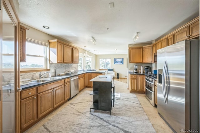 kitchen featuring a breakfast bar, a center island, sink, decorative backsplash, and appliances with stainless steel finishes