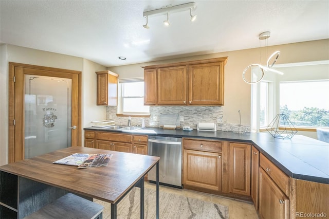 kitchen featuring dishwasher, sink, decorative light fixtures, track lighting, and decorative backsplash