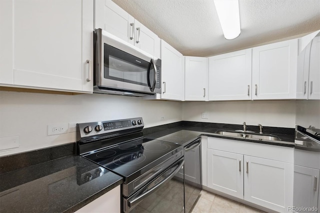 1029 E 8th Ave Unit 603, Denver, CO 80218 - kitchen featuring stainless steel appliances, white cabinetry, dark stone countertops, a textured ceiling, and light tile patterned floors