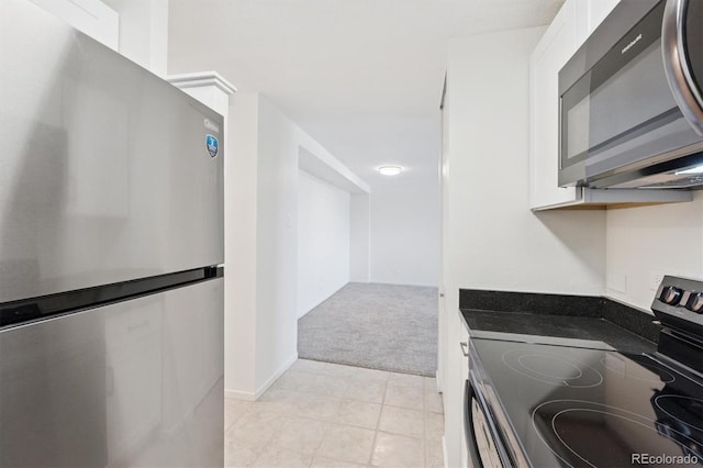 1029 E 8th Ave Unit 603, Denver, CO 80218 - kitchen featuring appliances with stainless steel finishes, white cabinets, light carpet, dark countertops, and light tile patterned floors