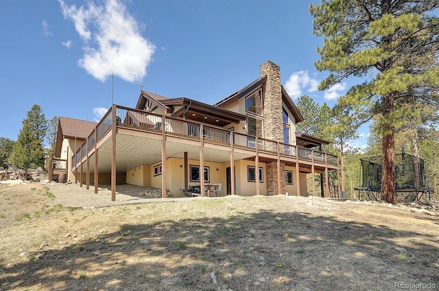 30220 Columbia Pt, Buena Vista, CO 81211 - rear view of property with a trampoline, a deck, stucco siding, and a chimney