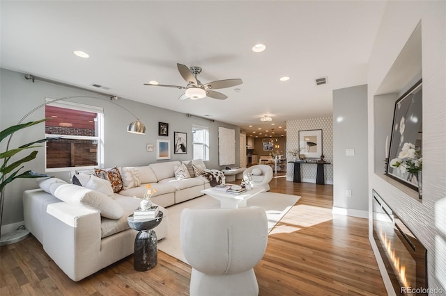 living room with recessed lighting, visible vents, baseboards, and wood finished floors