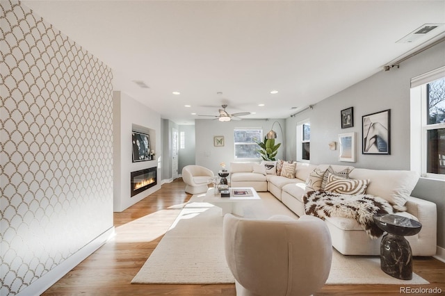 living area featuring recessed lighting, a large fireplace, visible vents, and light wood-style flooring