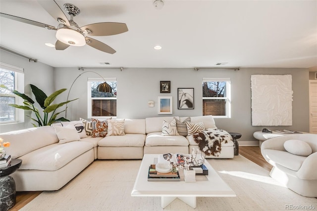 living area featuring visible vents, ceiling fan, baseboards, and wood finished floors