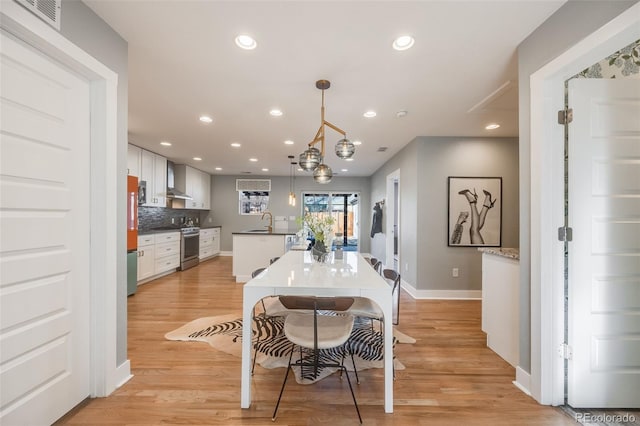 kitchen featuring stainless steel range with gas cooktop, white cabinets, a sink, and a center island with sink