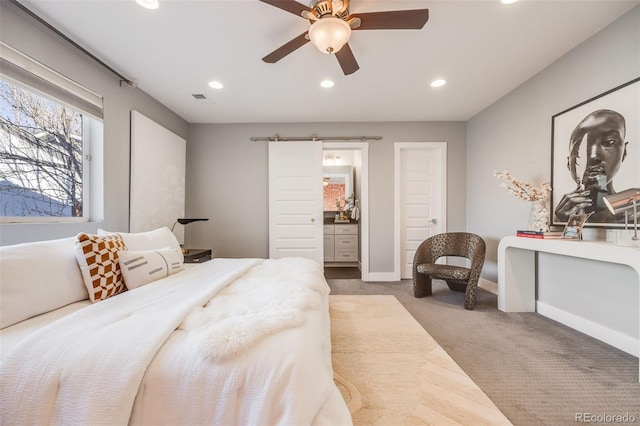 carpeted bedroom featuring ceiling fan, ensuite bathroom, a barn door, recessed lighting, and baseboards