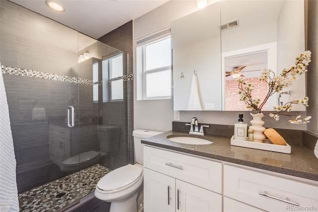 full bath featuring toilet, vanity, visible vents, and a shower stall