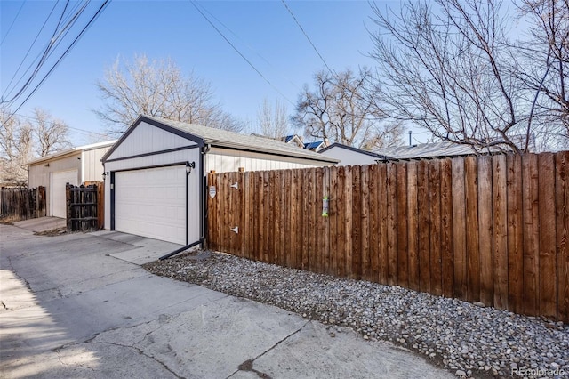 view of side of property featuring an outdoor structure, fence, and a detached garage