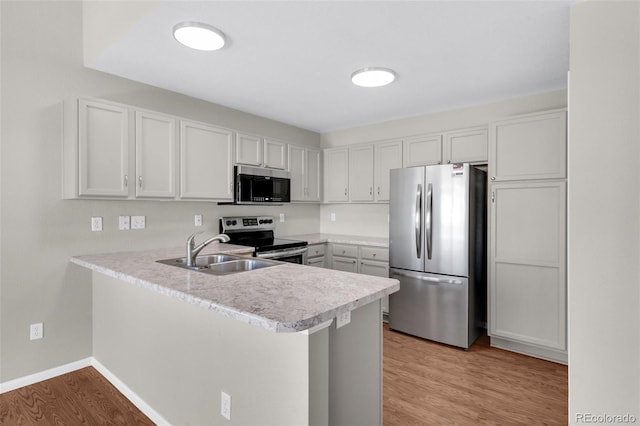 3456 Osprey Ridge Dr, Colorado Springs, CO 80916 - kitchen featuring stainless steel appliances, a sink, a peninsula, light countertops, and light wood-type flooring