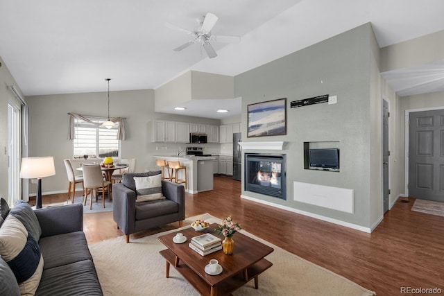 3456 Osprey Ridge Dr, Colorado Springs, CO 80916 - living room with vaulted ceiling, baseboards, wood finished floors, a ceiling fan, and a multi sided fireplace