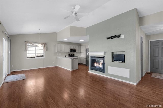 3456 Osprey Ridge Dr, Colorado Springs, CO 80916 - unfurnished living room featuring lofted ceiling, baseboards, dark wood-style flooring, ceiling fan, and a sink