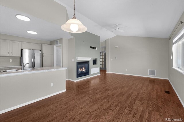 3456 Osprey Ridge Dr, Colorado Springs, CO 80916 - unfurnished living room with a sink, ceiling fan, lofted ceiling, dark wood-style flooring, and a glass covered fireplace