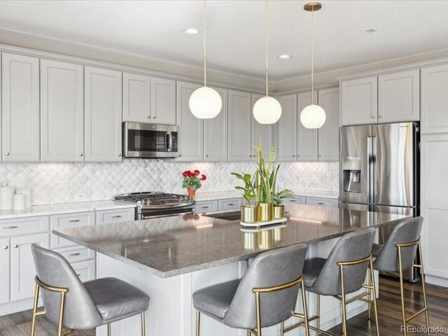 11426 Box Turtle Ct, Parker, CO 80134 - kitchen featuring appliances with stainless steel finishes, a kitchen island, decorative backsplash, hanging light fixtures, and recessed lighting