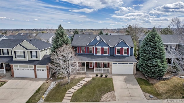 traditional home featuring a garage, covered porch, a residential view, and concrete driveway