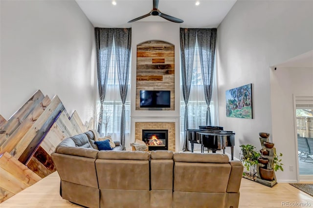 living room featuring a ceiling fan, wood finished floors, baseboards, a brick fireplace, and recessed lighting