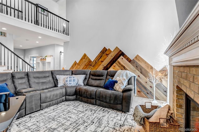 living area featuring a high ceiling, a brick fireplace, stairs, and recessed lighting