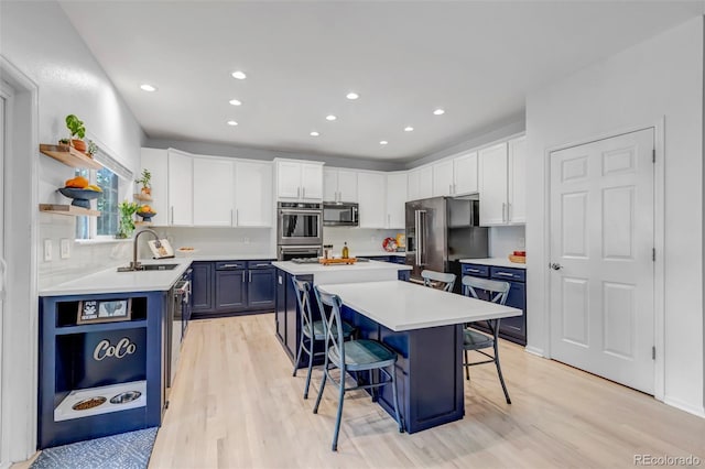 kitchen featuring a kitchen breakfast bar, open shelves, blue cabinets, appliances with stainless steel finishes, and a kitchen island