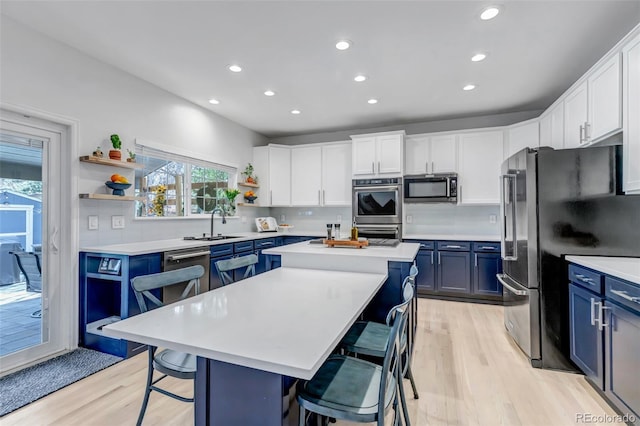 kitchen with stainless steel appliances, a center island, a kitchen bar, blue cabinetry, and open shelves