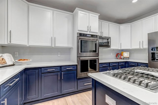 kitchen with blue cabinets, white cabinets, stainless steel appliances, and light countertops