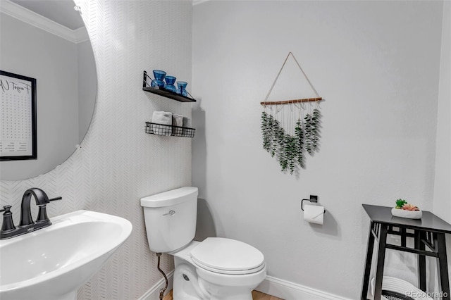 bathroom featuring baseboards, a sink, ornamental molding, and toilet