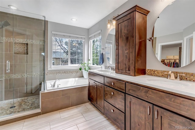 bathroom with double vanity, a bath, a stall shower, and a sink