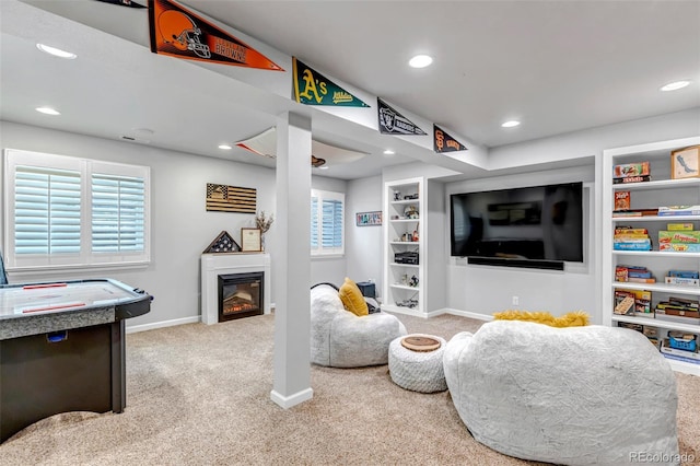 carpeted living room featuring a glass covered fireplace, baseboards, recessed lighting, and built in features