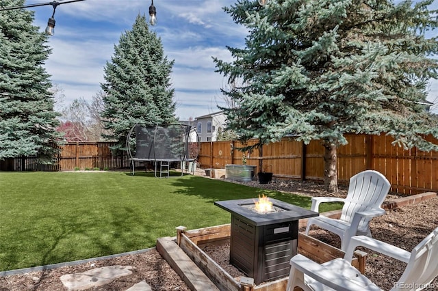 view of yard with a fenced backyard, an outdoor fire pit, and a trampoline
