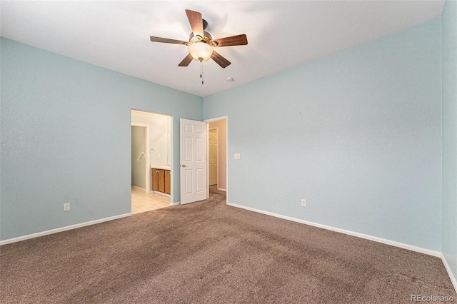 unfurnished bedroom featuring ceiling fan, light colored carpet, and ensuite bath