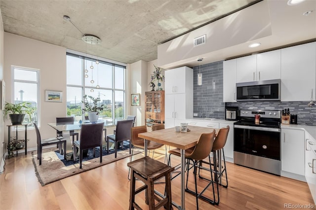 1700 Bassett St Unit 513, Denver, CO 80202 - kitchen with stainless steel appliances, light wood-style floors, tasteful backsplash, and light countertops