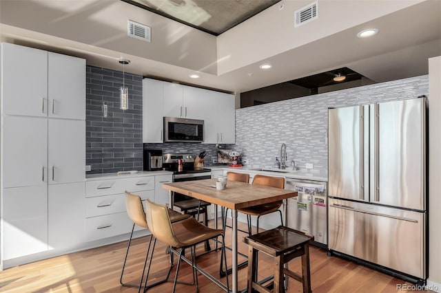 1700 Bassett St Unit 513, Denver, CO 80202 - kitchen featuring stainless steel appliances, a sink, light wood finished floors, tasteful backsplash, and recessed lighting